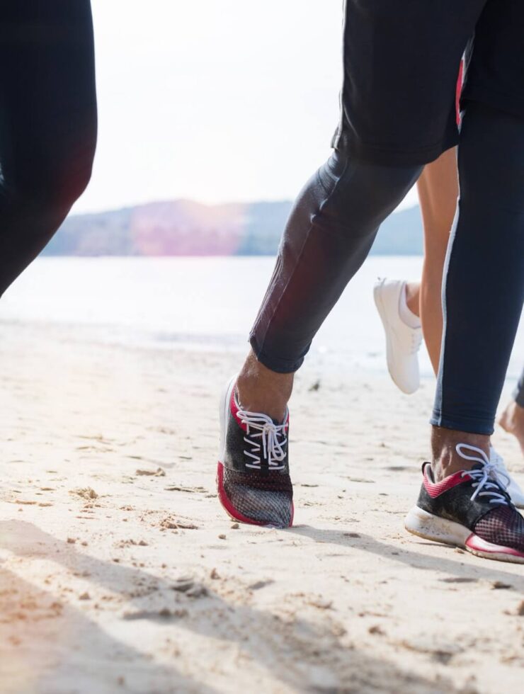 Closeup Of Group Of People Running On Beach Feet Shot Sport Runners Jogging Working Out Team Men And