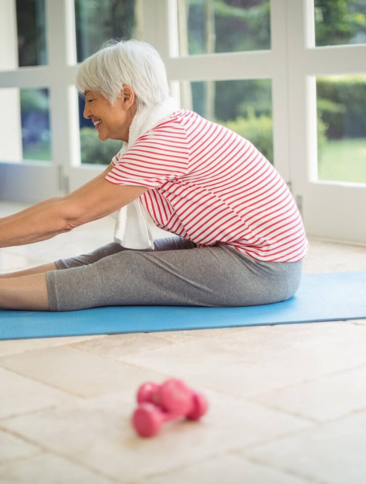 Senior woman performing stretching exercise at home