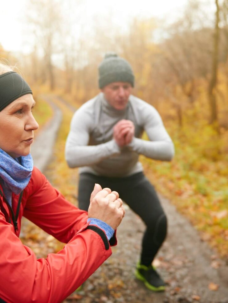 Athletic couple doing squats among forest