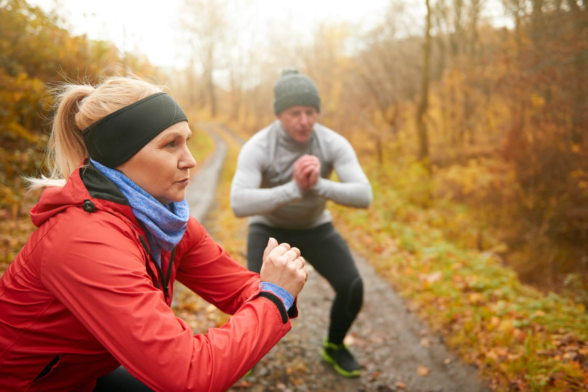 Athletic couple doing squats among forest