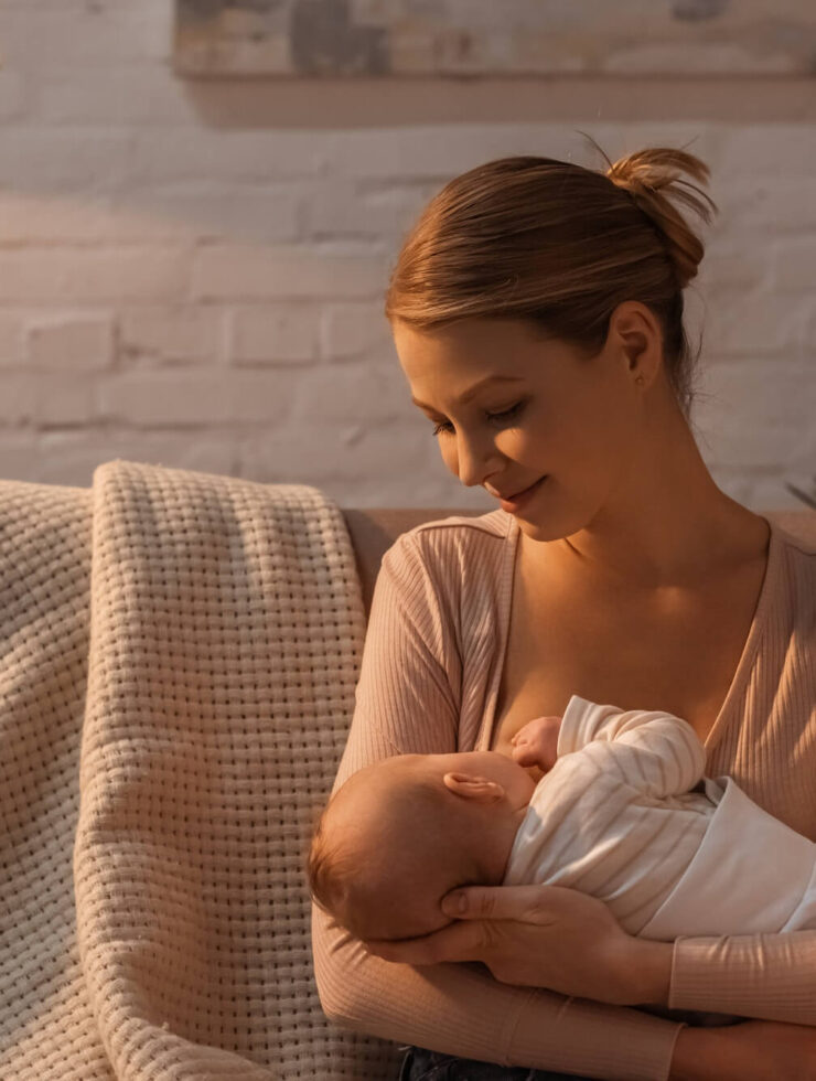 smiling young mother breastfeeding baby at night