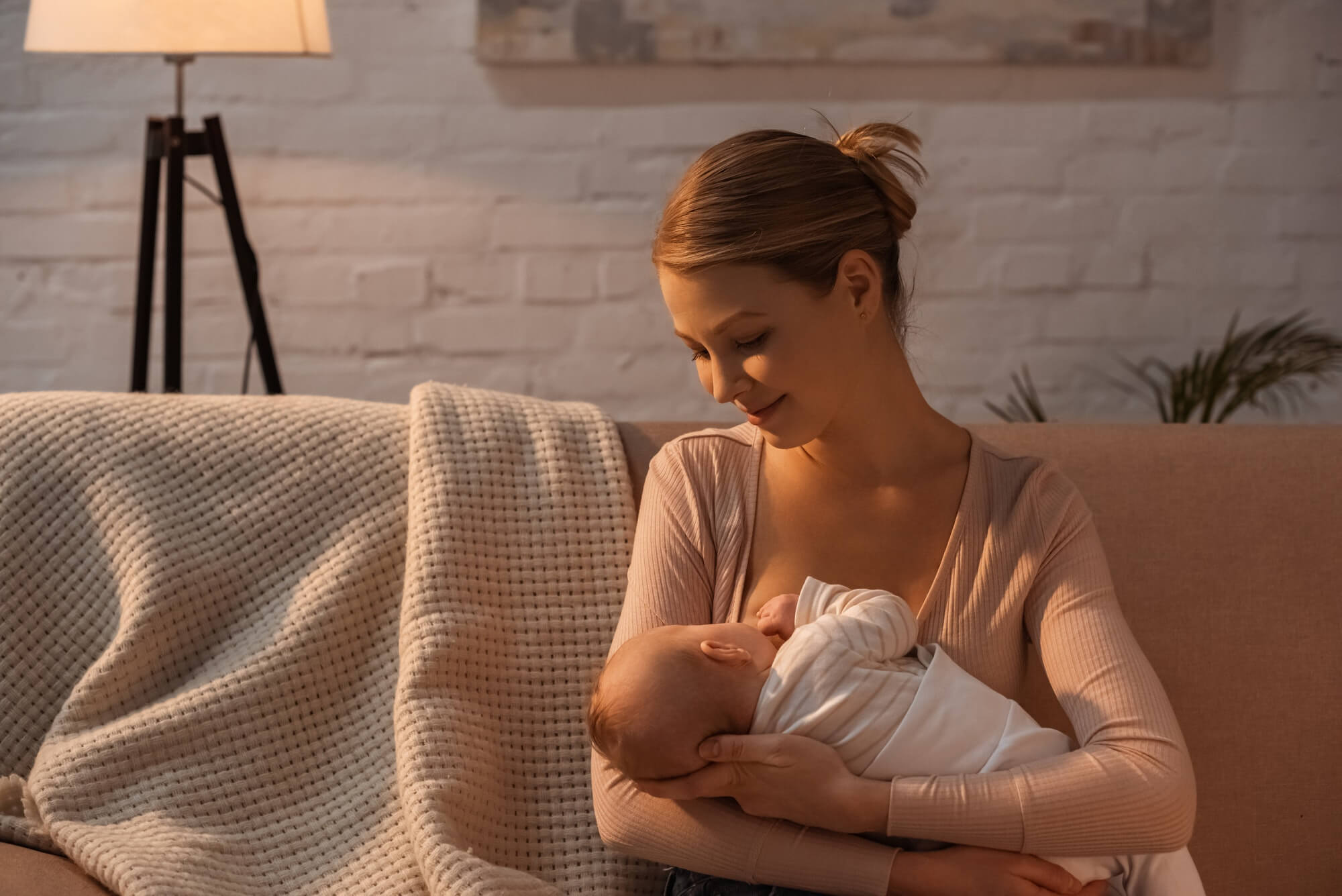 smiling young mother breastfeeding baby at night